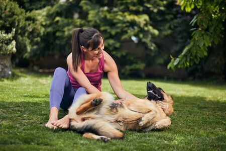 Young attractive fit yogi brunette playing with her dog in backyard.の写真素材