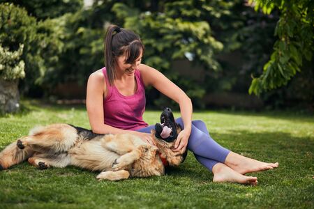 Young attractive fit yogi brunette playing with her dog in backyard.の写真素材
