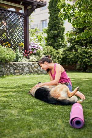 Young attractive fit yogi brunette playing with her dog in backyard.の写真素材