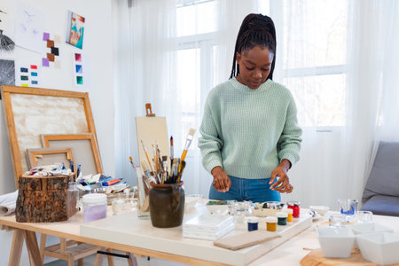 african american woman painting picture at home on easel at homeの写真素材
