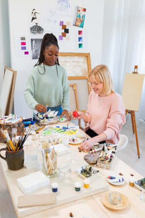 african american teacher helping senior student to paint in art studioの写真素材