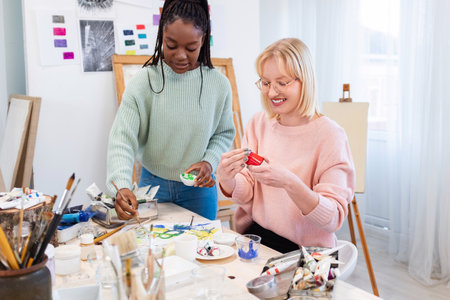 Smiling female artist showing her work to her female colleague in workshopの写真素材