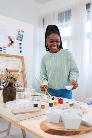 Portrait of smiling female artist painting picture on canvas in art studioの写真素材
