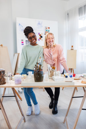 Portrait of smiling female artist with colleague in creative studio at deskの写真素材