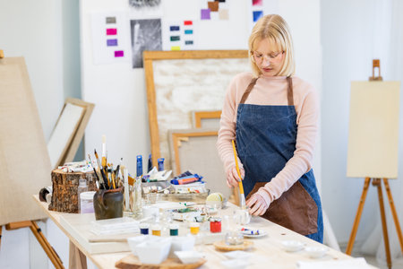 Portrait of female artist painting picture on easel in art studioの写真素材