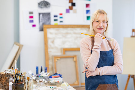 Portrait of mature female artist standing with arms crossed in art studioの写真素材