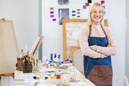 Portrait of smiling female artist standing with arms crossed in art studioの写真素材