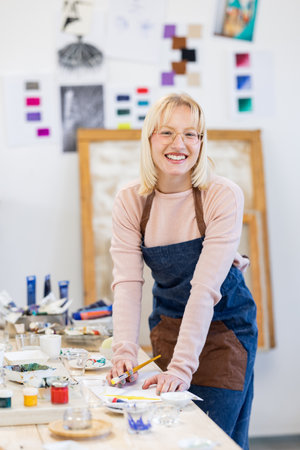 Portrait of smiling female artist working on her masterpiece in art studioの写真素材