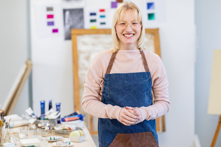 Portrait of smiling female artist standing with arms crossed in art studioの写真素材