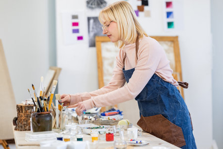Portrait of a female artist painting on canvas in her studio.の写真素材