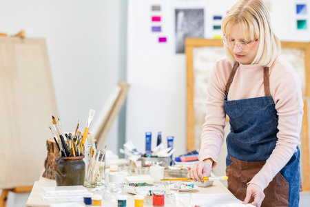 Portrait of a female artist painting on canvas in her studio.の写真素材