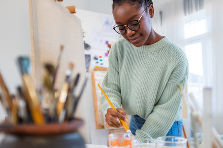 Portrait of smiling female artist drawing on canvas in studio at homeの写真素材