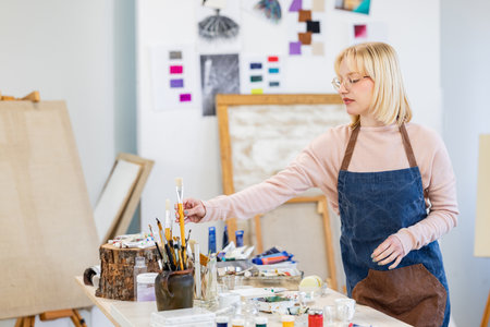 Portrait of a mature female artist painting on canvas in her studioの写真素材