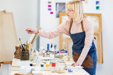 Woman painting on canvas in art studio. Female artist painting picture on canvas.の写真素材