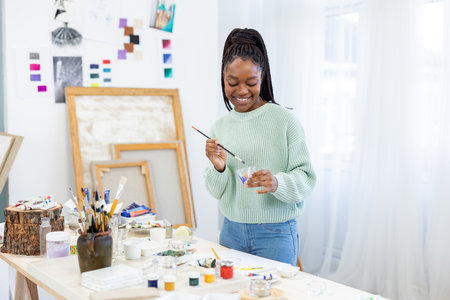 african american woman painting picture at home in front of easelの写真素材