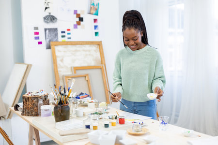 african american woman painting on easel at art class or workshopの写真素材