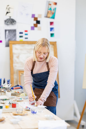 Senior woman painting on canvas in art studio, shallow depth of fieldの写真素材