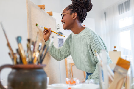 african american artist painting picture in art studio at creative workplaceの写真素材