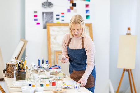 Portrait of a female artist painting on canvas in her studio.の写真素材