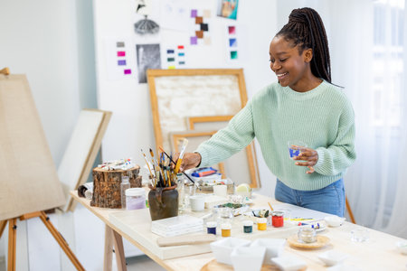 african american female artist painting picture on easel at studioの写真素材