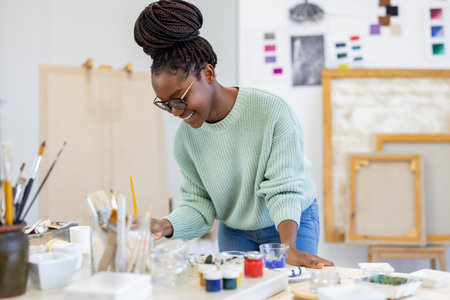 african american female artist painting picture on canvas in art studioの写真素材