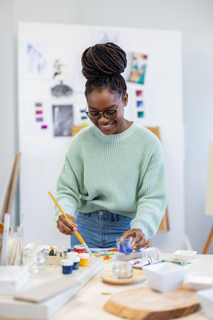 Portrait of smiling female artist painting picture in workshop at creative studioの写真素材