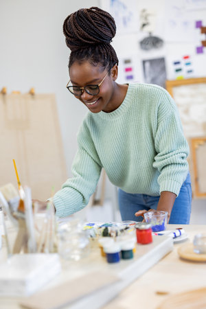 Portrait of smiling female artist painting in art studio at creative workplaceの写真素材