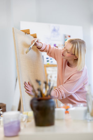 Portrait of a female artist painting on canvas in her studio.の写真素材