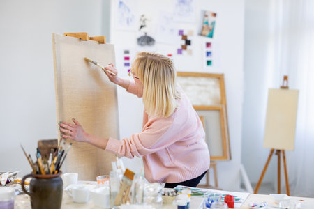 Female artist painting on canvas in art studio. Young woman painting on canvas.の写真素材