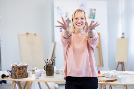 Portrait of smiling female artist standing in art studio with hands upの写真素材