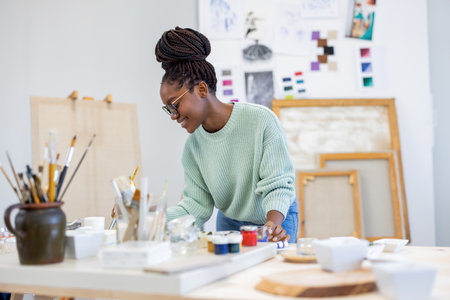 Portrait of female artist working on painting in creative studio at deskの写真素材