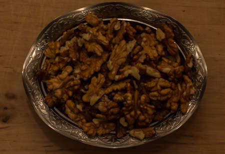 Walnut kernels on a wooden background. In a silver bowl.