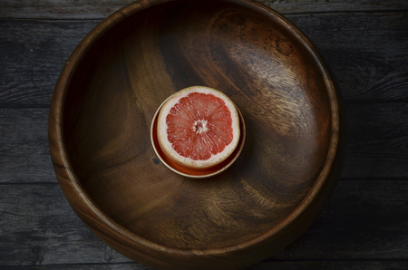 Sliced fresh grapefruit in wooden bowl. Top viewの写真素材