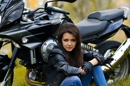 Beautiful biker girl, snorting biker girl, stunning biker girl, attractive biker girl, nice biker girl with leather jacket, modern, new, black motorcycle, motorbike, long hair, sitting on road near motorbike.Professional beautiful, serious, dangerous bossの写真素材