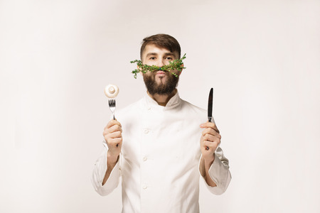 Chef's menu logo. Vegan restaurant logo. Symbol of healthy food. CONCEPT OF HEALTHY FOOD. Handsome funny cheff holding spoon and knife and herbs like a mustache. Professional chef.の写真素材