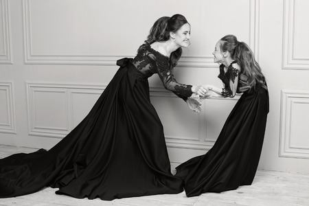 Mother and daughter hugging and looking at the camera. Happy loving family. Mother and daughter in beautiful long luxury blue dresses, makeup hairstyle. Fashion family portait. Generation relationshipの写真素材