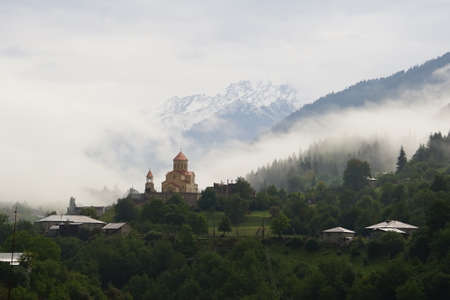Mountain landscape with a church in the foreground and fog in the background