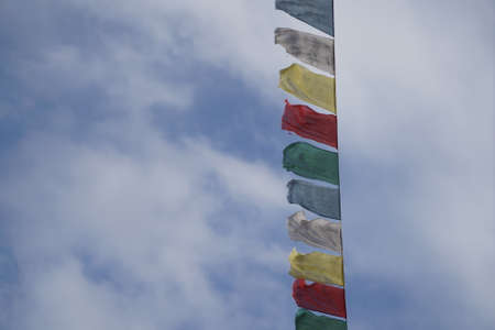 Buddhist prayer flags with blue sky and white clouds background.