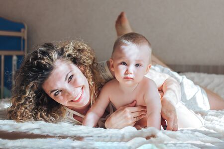 mother and baby lie on bedの写真素材