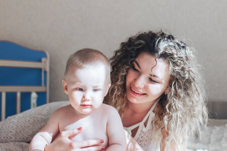mother and baby hugging and lie on bedの写真素材