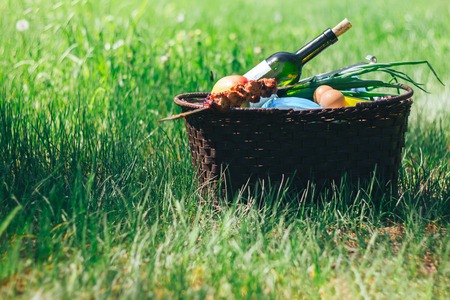 picnic basket on green lawn with bottle of wineの写真素材