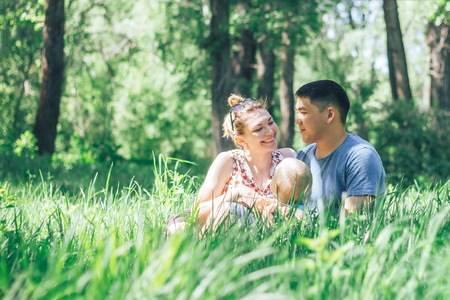happy young family spending time outdoor on a summer day mother and father looking each other and son sitting near themの写真素材