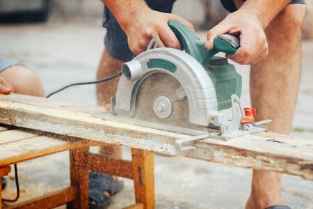 A man using a circular saw to cut the woodの写真素材