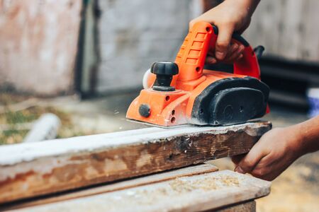 Carpenter chipping the wooden plank for taking off the old paintの写真素材