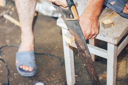 Portrait of mid adult manual worker sawing wood at construction siteの写真素材