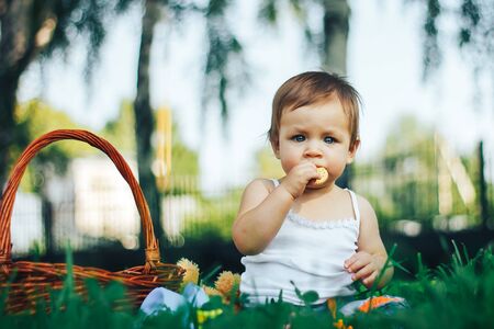 baby eating a biscuit or cookies on grass in a parkの写真素材