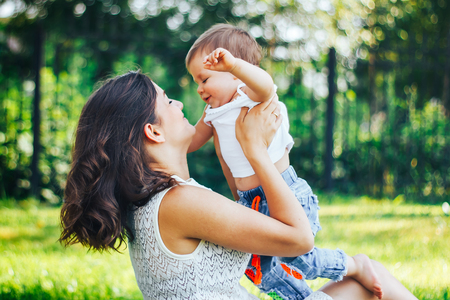 Happy loving mother and her baby child playing outdoors in the parkの写真素材