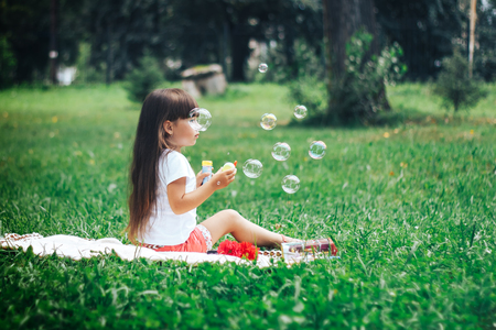 Little beautiful girl blowing soap bubbleの写真素材