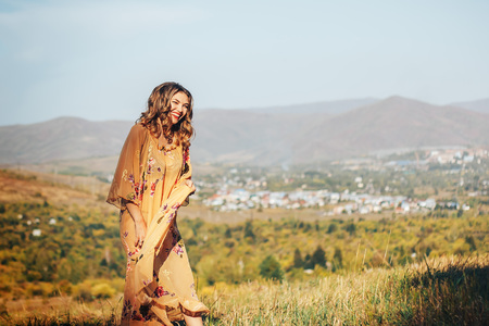 dancing laughing woman in yellow dress on field on city or country backgroundの写真素材