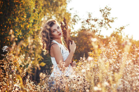Young woman with a flowers in autumn fieldの写真素材